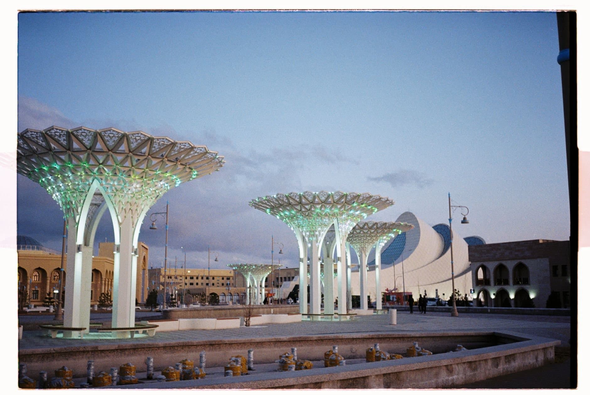 Futuristic urban landscape with modern architecture in Turkestan, featuring illuminated structures at dusk.