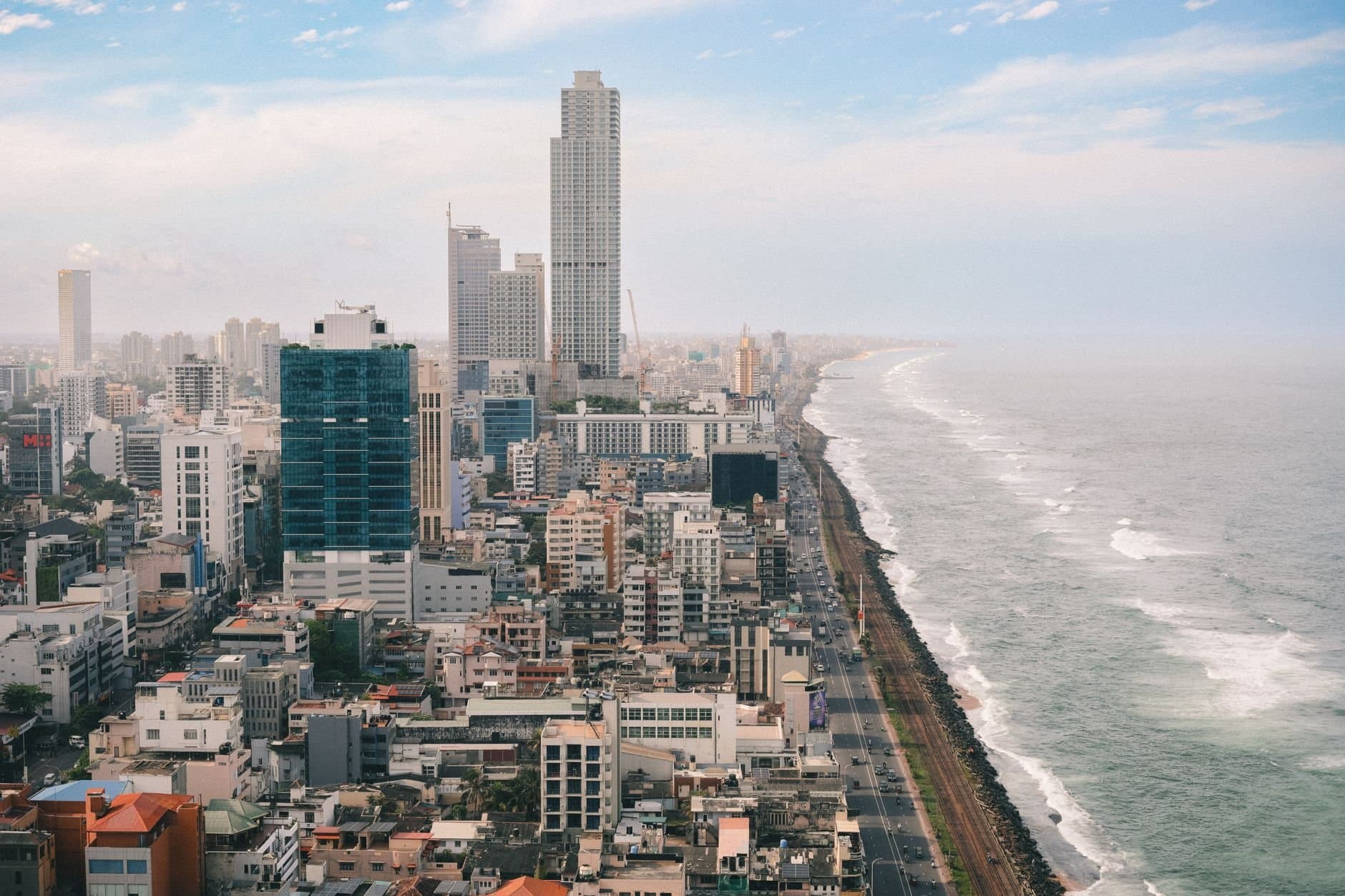 Aerial view of Colombo's vibrant skyline against the Indian Ocean's dramatic waves.