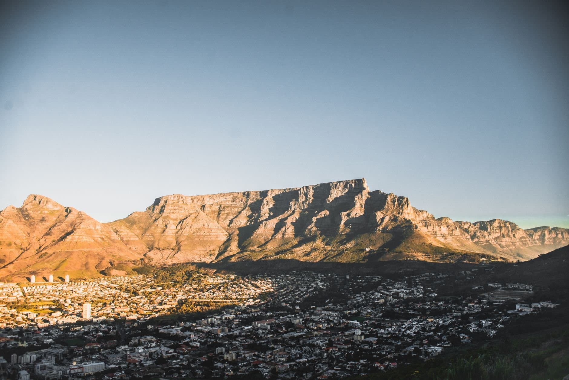 A breathtaking view of Cape Town's cityscape with the iconic Table Mountain in the backdrop during sunset.