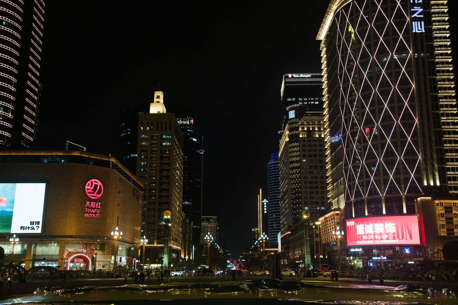 Night view of Chengdu cityscape featuring illuminated skyscrapers and bustling streets.