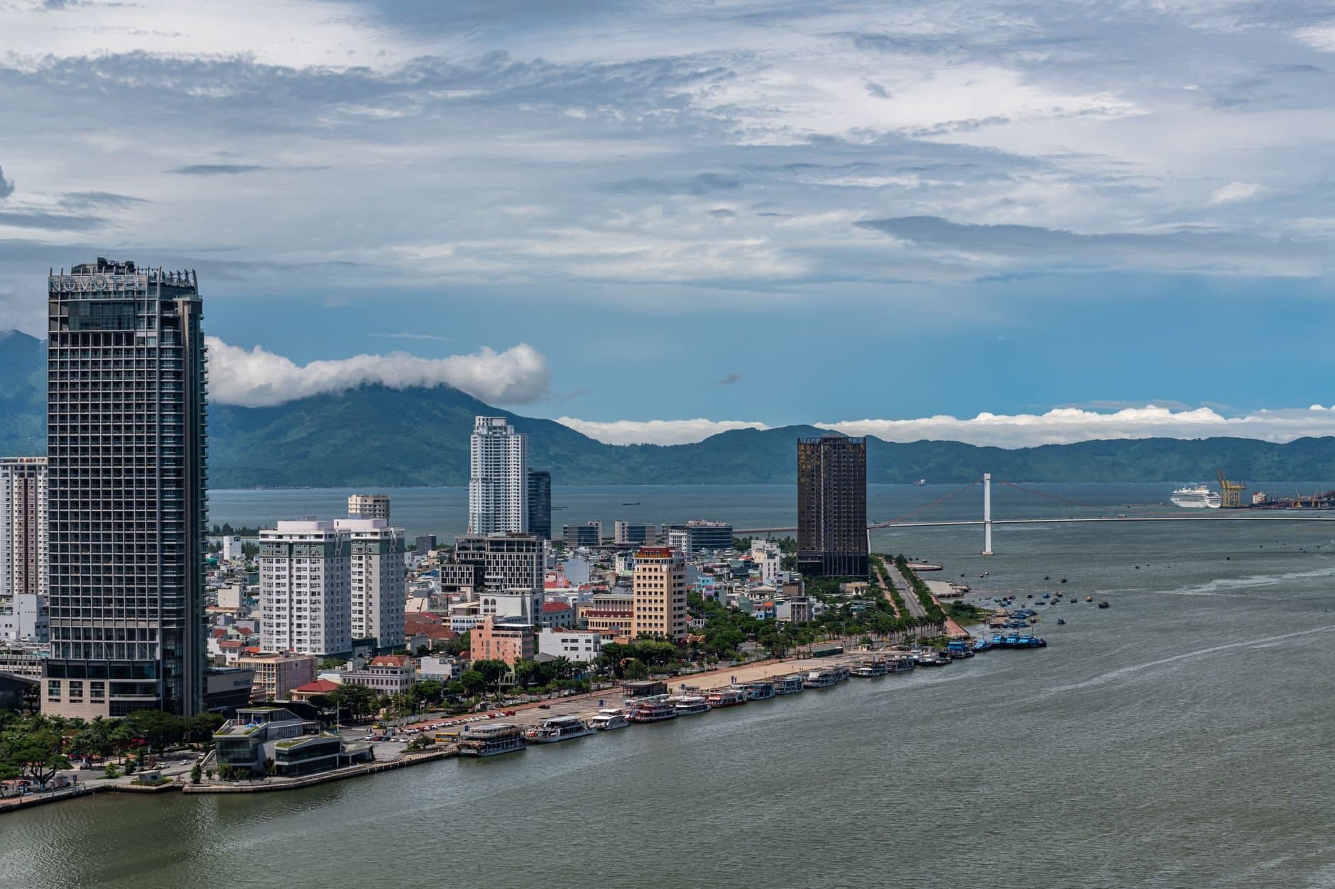 Scenic aerial view of Da Nang's urban skyline and coastline against a mountainous backdrop.