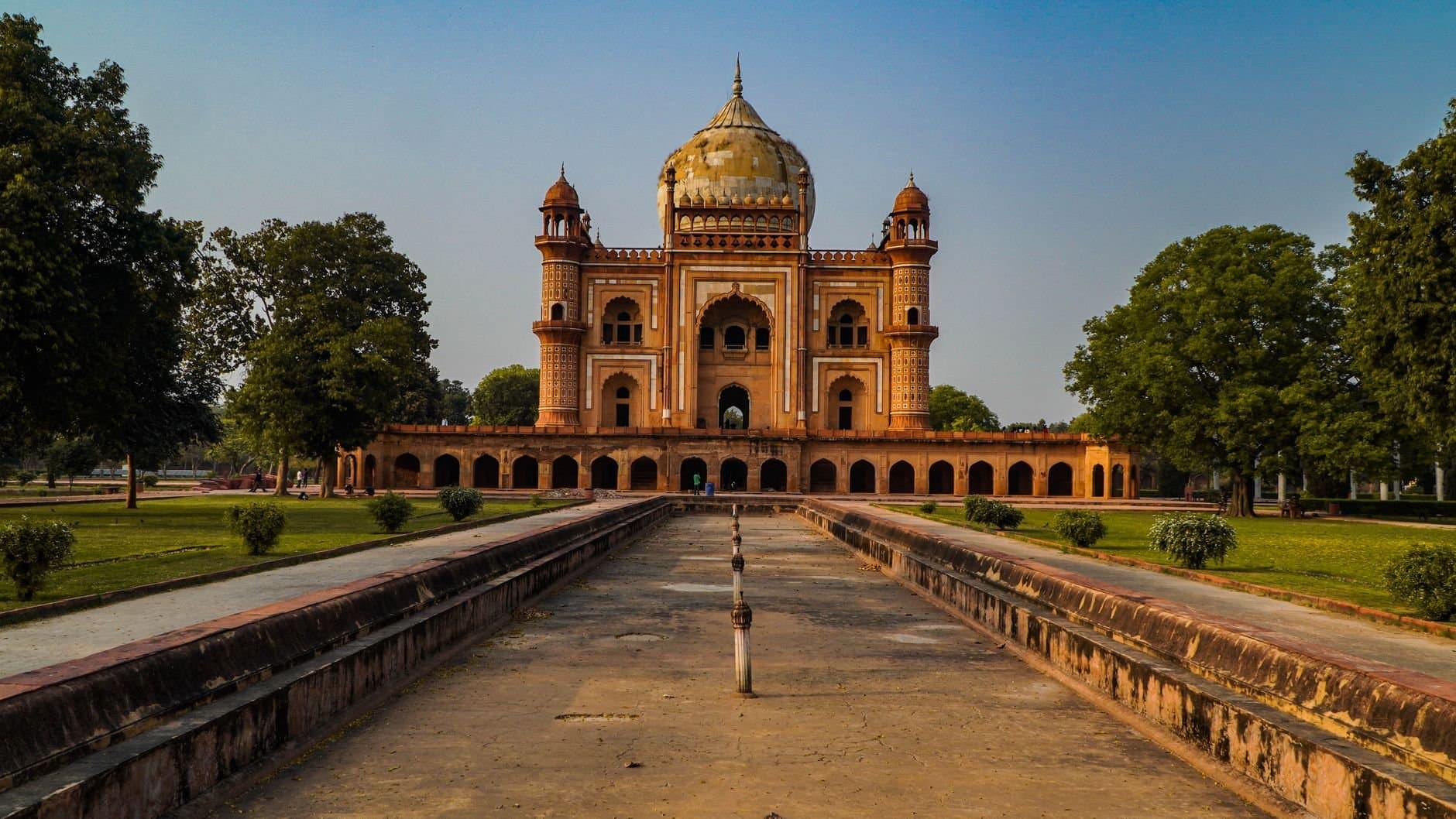 Stunning view of Safdarjung Tomb in New Delhi, India, captured at sunset with clear skies and lush greenery.