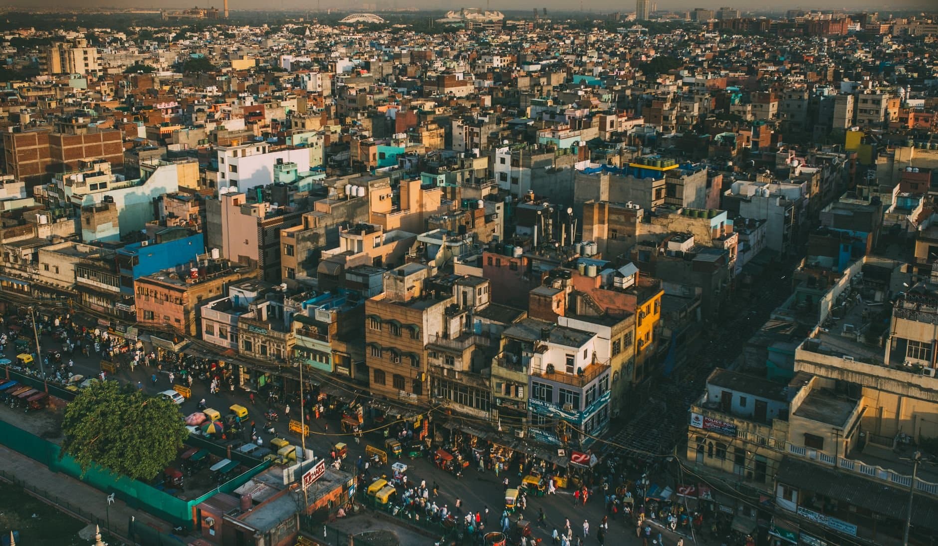 A vibrant aerial cityscape of Delhi, showcasing the bustling streets and diverse architecture under warm daylight.