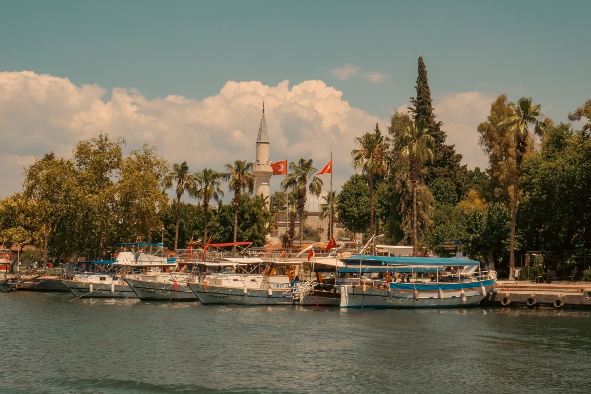 Charming view of boats docked by Boğaziçi Mosque in Dalaman, Türkiye, during a sunny summer day.