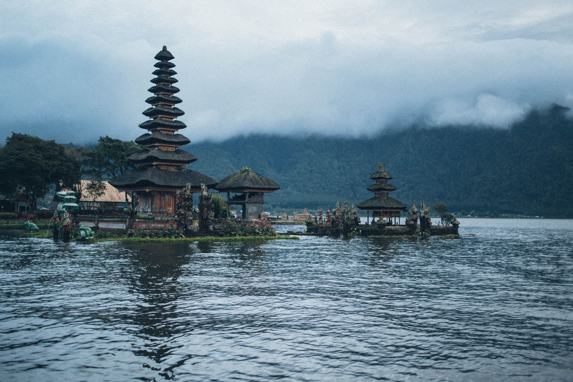 A serene view of Ulun Danu Beratan Temple on Lake Bratan, Bali, surrounded by misty mountains and calm waters.