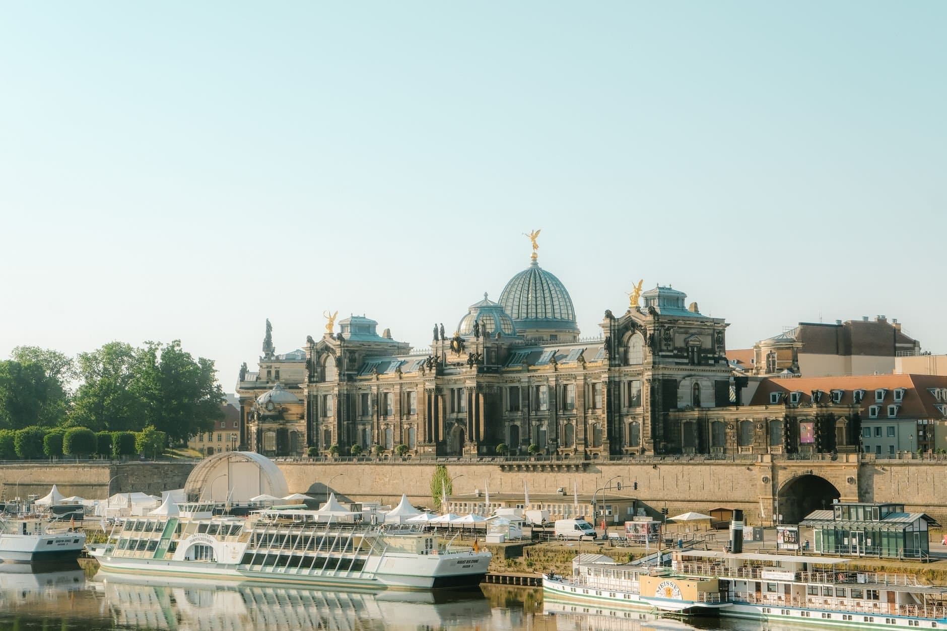 View of the Academy of Fine Arts Dresden with boats on the Elbe River under a clear sky.