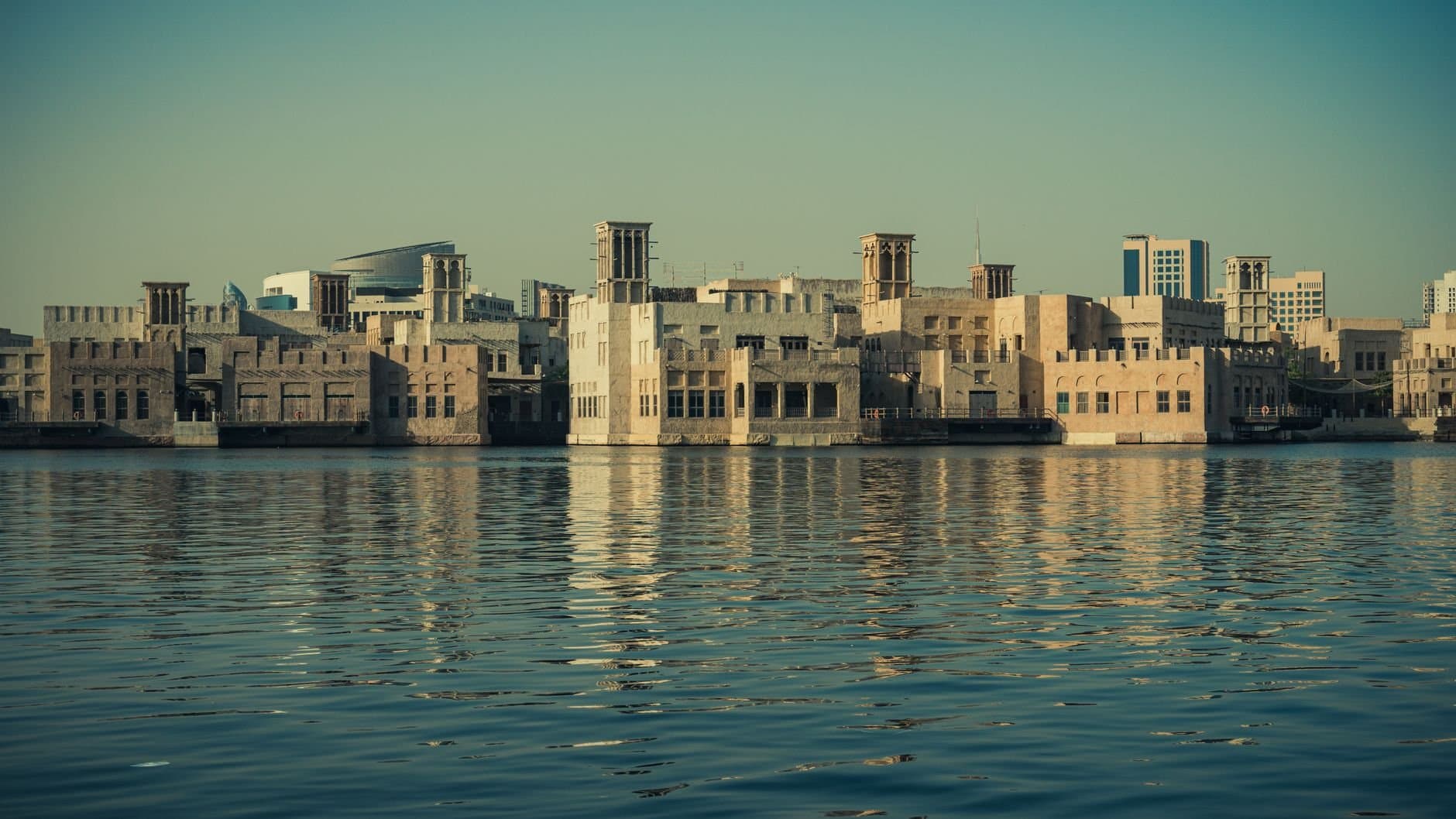Scenic view of modern architecture reflecting on the Dubai Creek waters, showcasing Dubai's waterfront skyline.