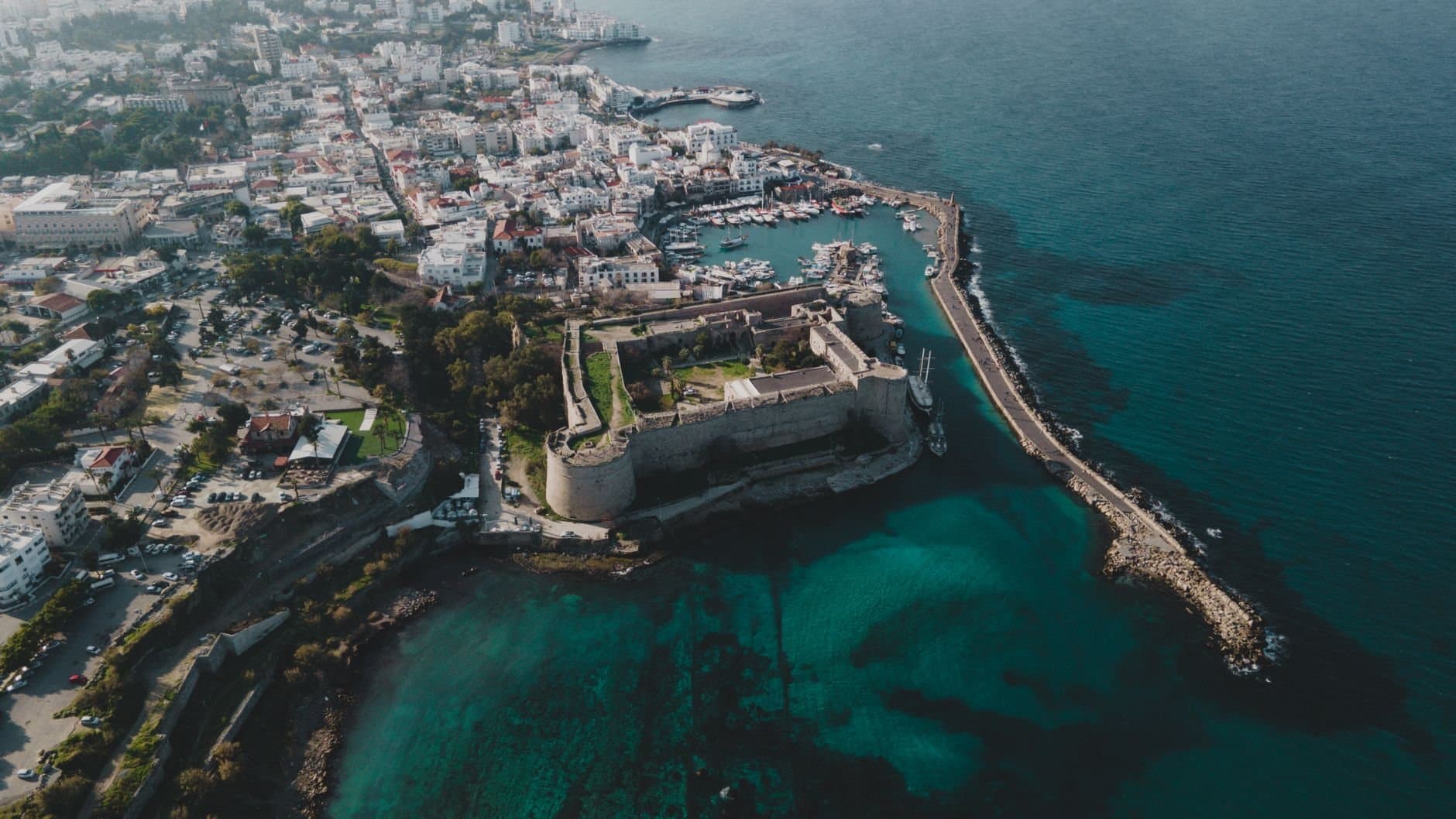Stunning aerial view of a coastal city featuring a historic castle and clear blue waters.