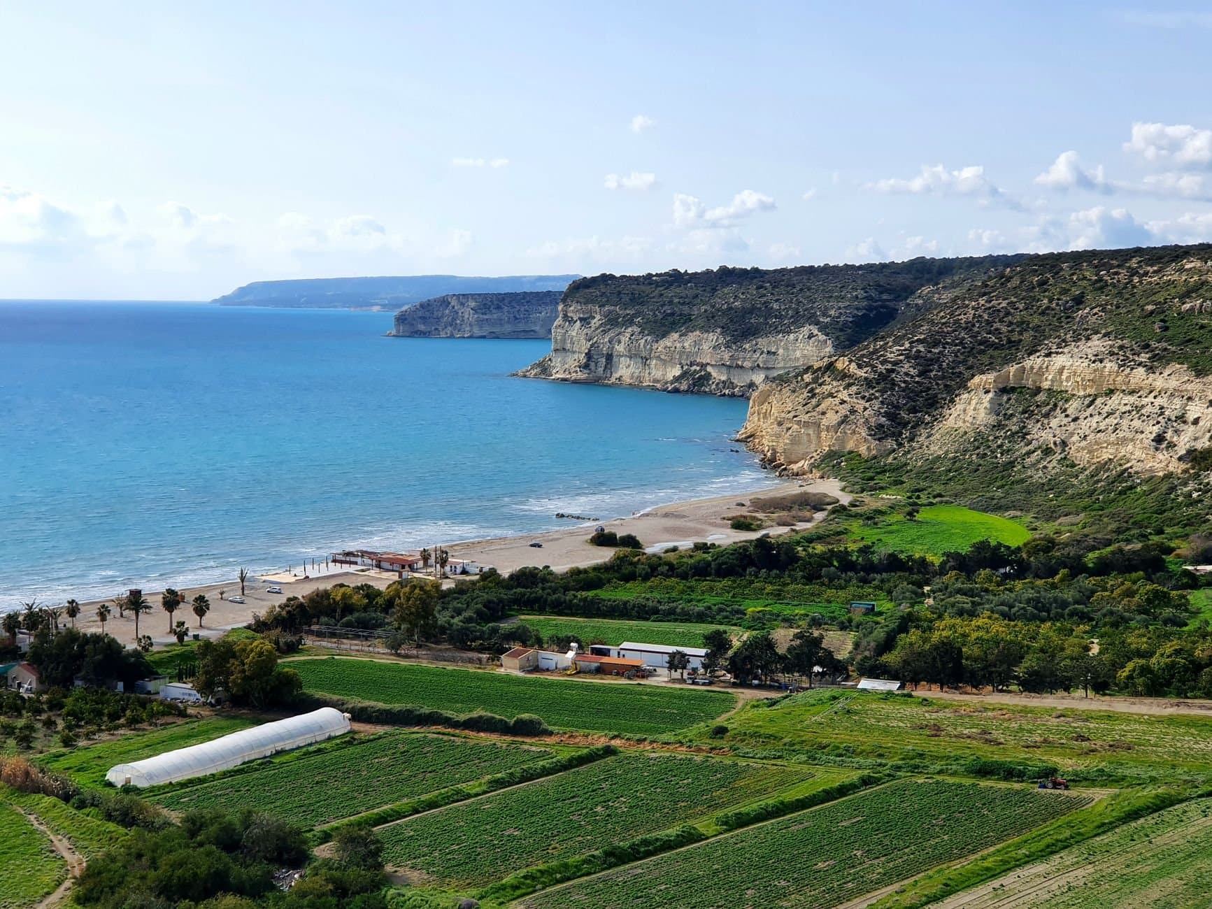 Beautiful coastal landscape featuring cliffs, green fields, and turquoise sea.