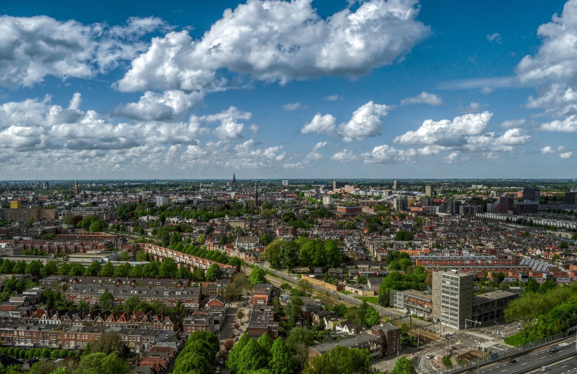 Aerial view of Groningen city skyline with a cloudy sky, showcasing urban architecture and green spaces.