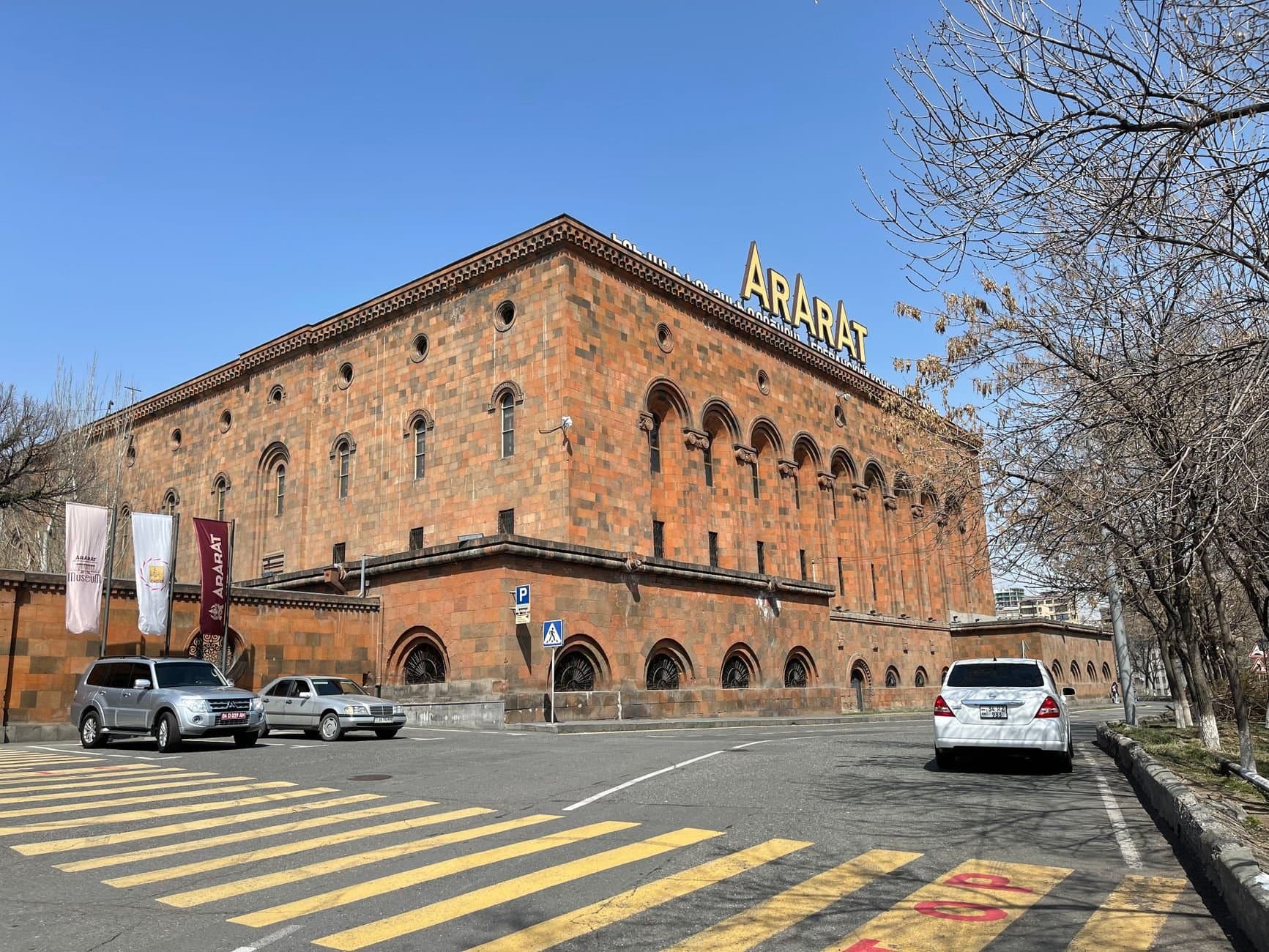 Exterior view of the iconic Ararat Brandy Factory in Yerevan, Armenia under a clear blue sky.
