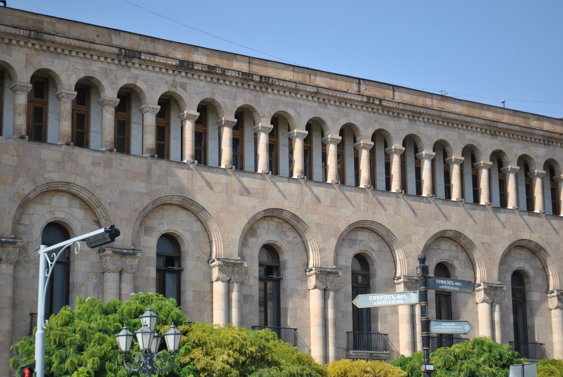 A classic architectural facade with arched windows, located in a lively urban area.