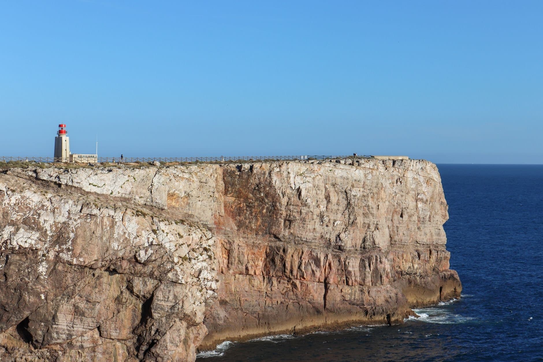 Stunning view of Sagres Point lighthouse on a rugged coastal cliff in Portugal.