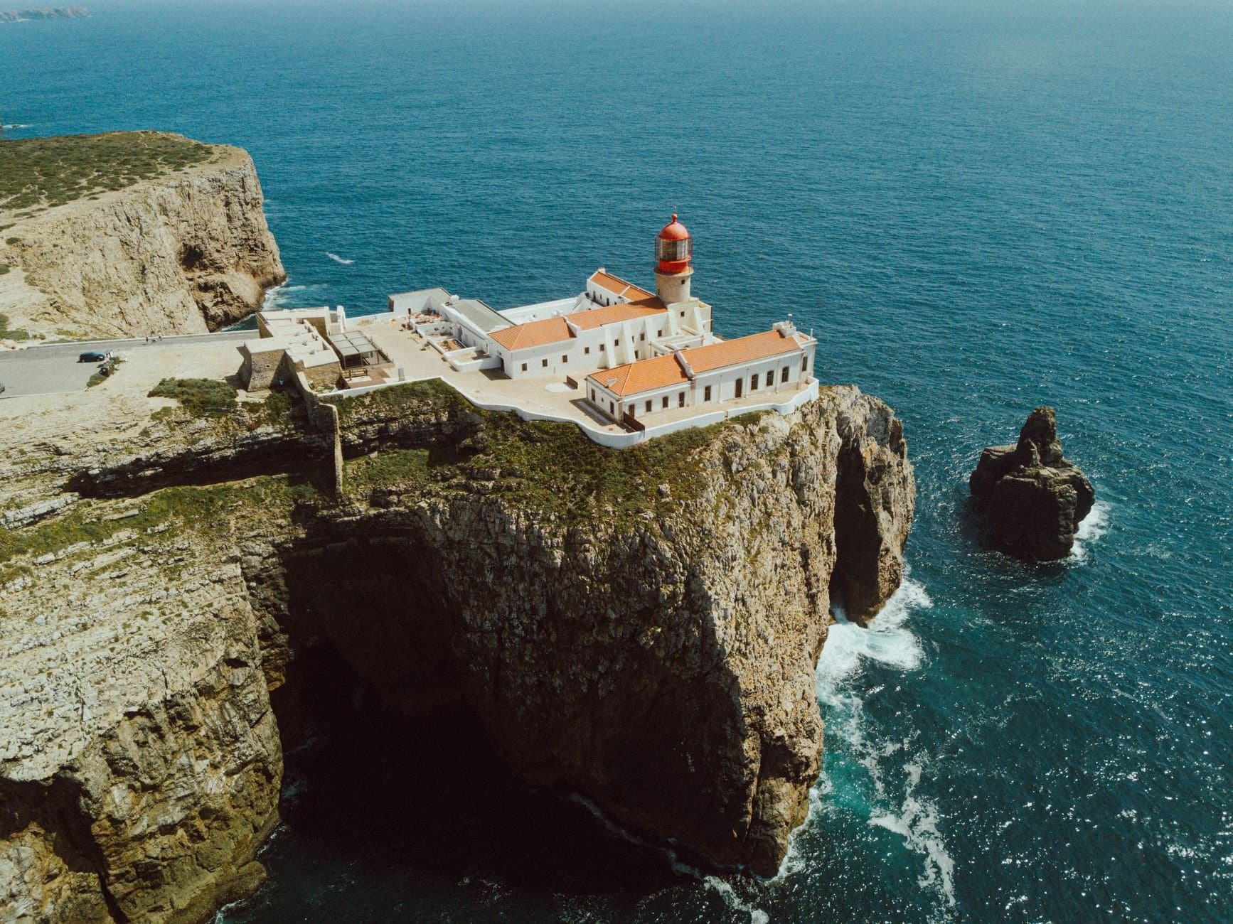 Dramatic aerial view of Cabo de São Vicente Lighthouse on cliffs in Portugal.