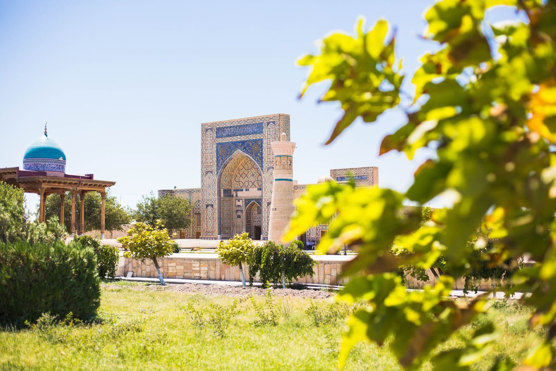 Explore the historic Gijduvon Madrasa amidst green foliage in Bukhara, Uzbekistan.