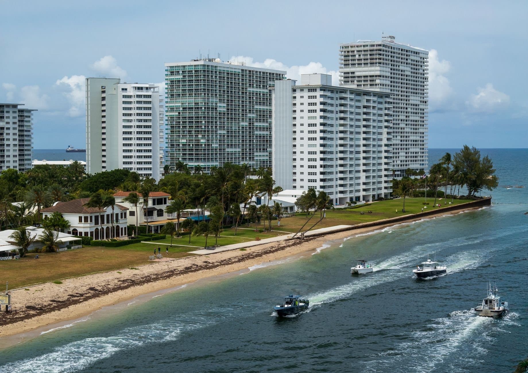 Aerial view of Fort Lauderdale high-rise buildings along the beach with boats on the water, exemplifying coastal city life.
