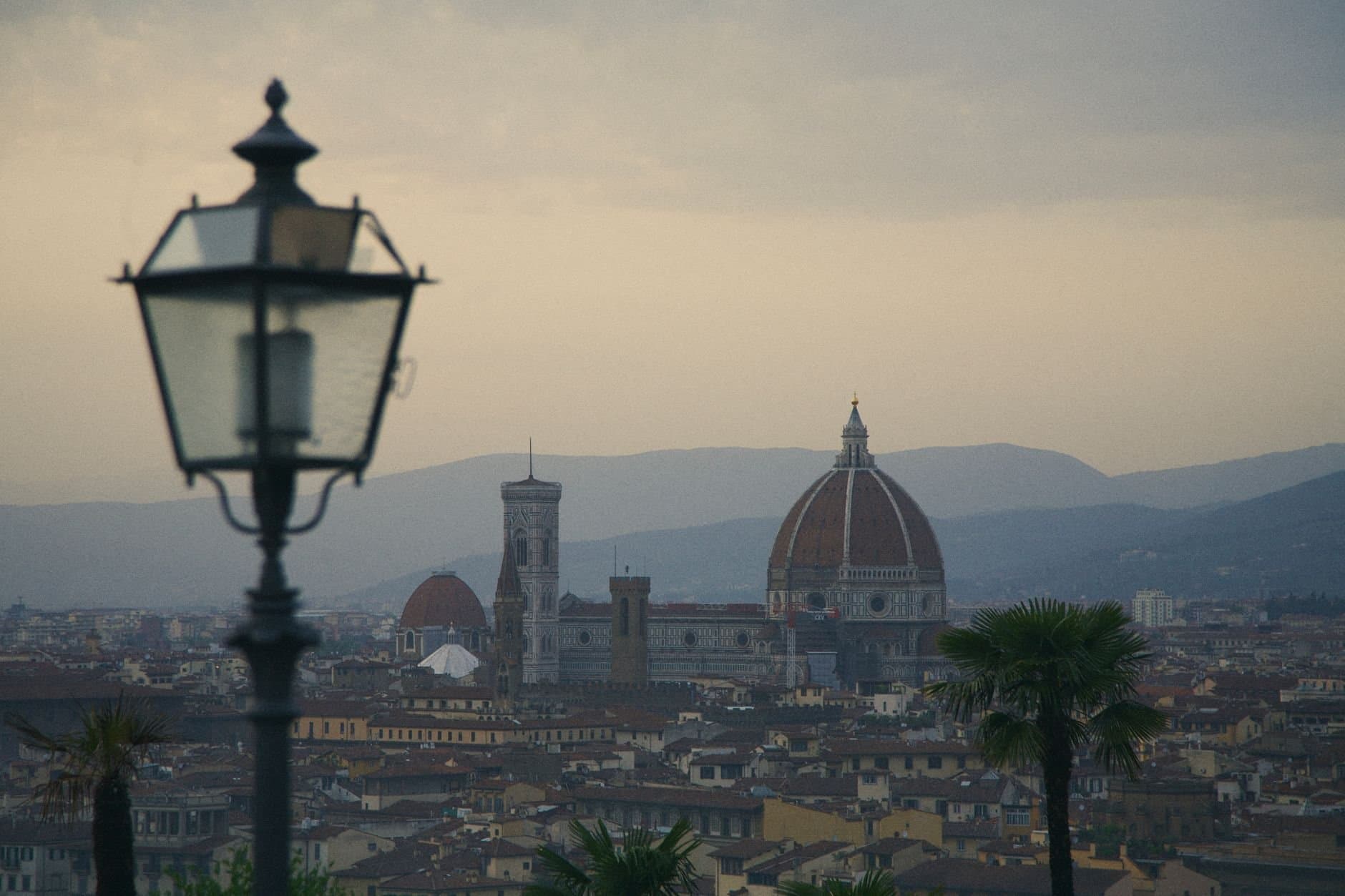 A view of Florence with the iconic Duomo and distant hills under a twilight sky.