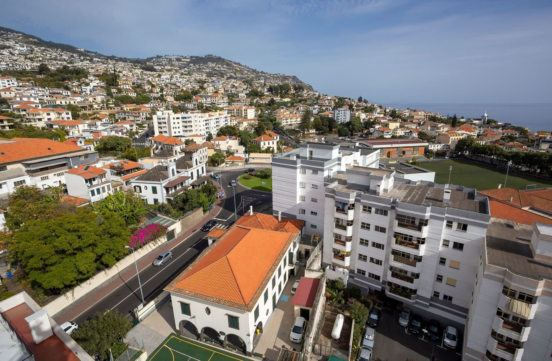 Aerial view of Funchal, Madeira showcasing red rooftops, residential buildings, and the coastline.