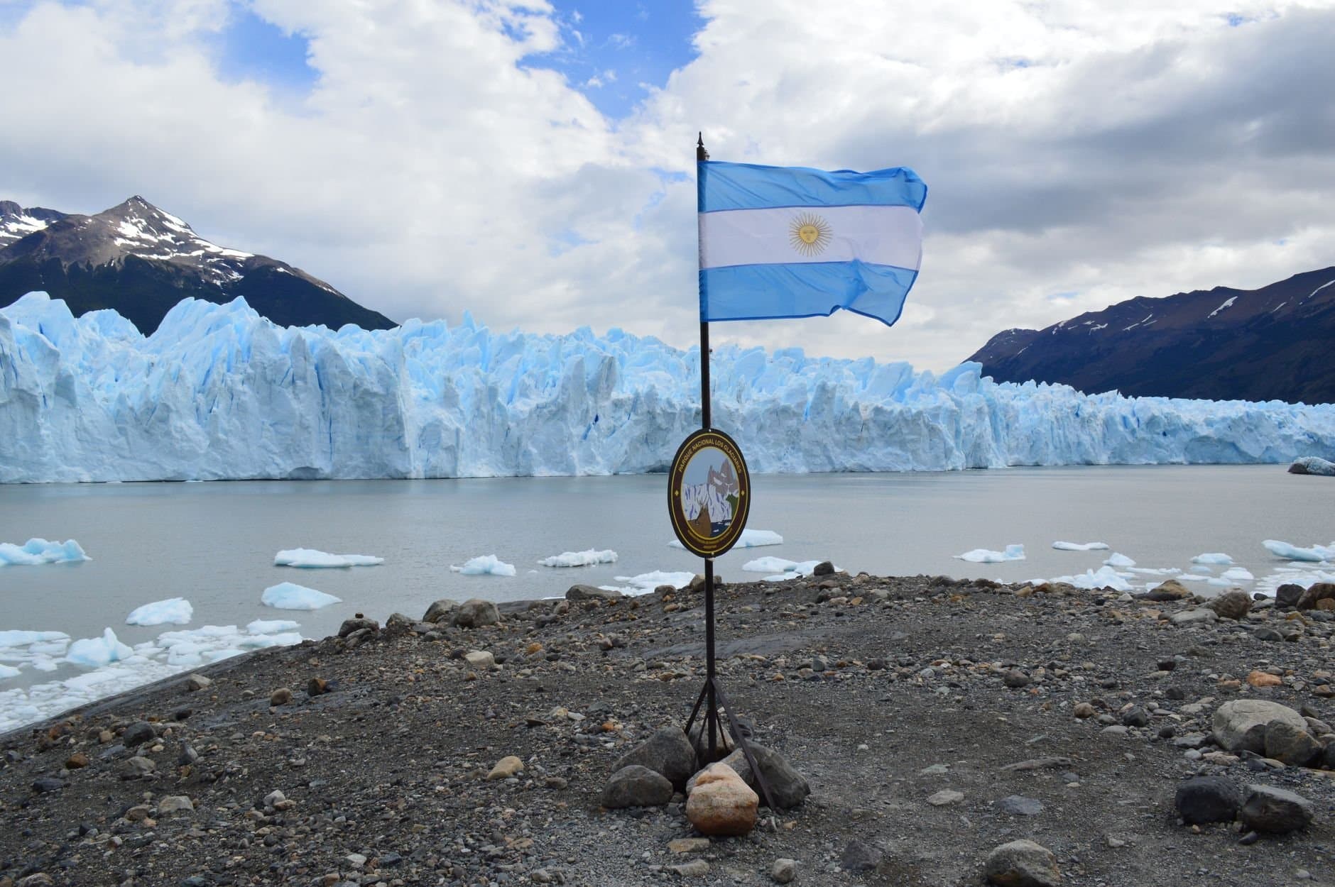 The iconic Perito Moreno Glacier with the Argentine flag, a stunning UNESCO World Heritage Site in Patagonia.