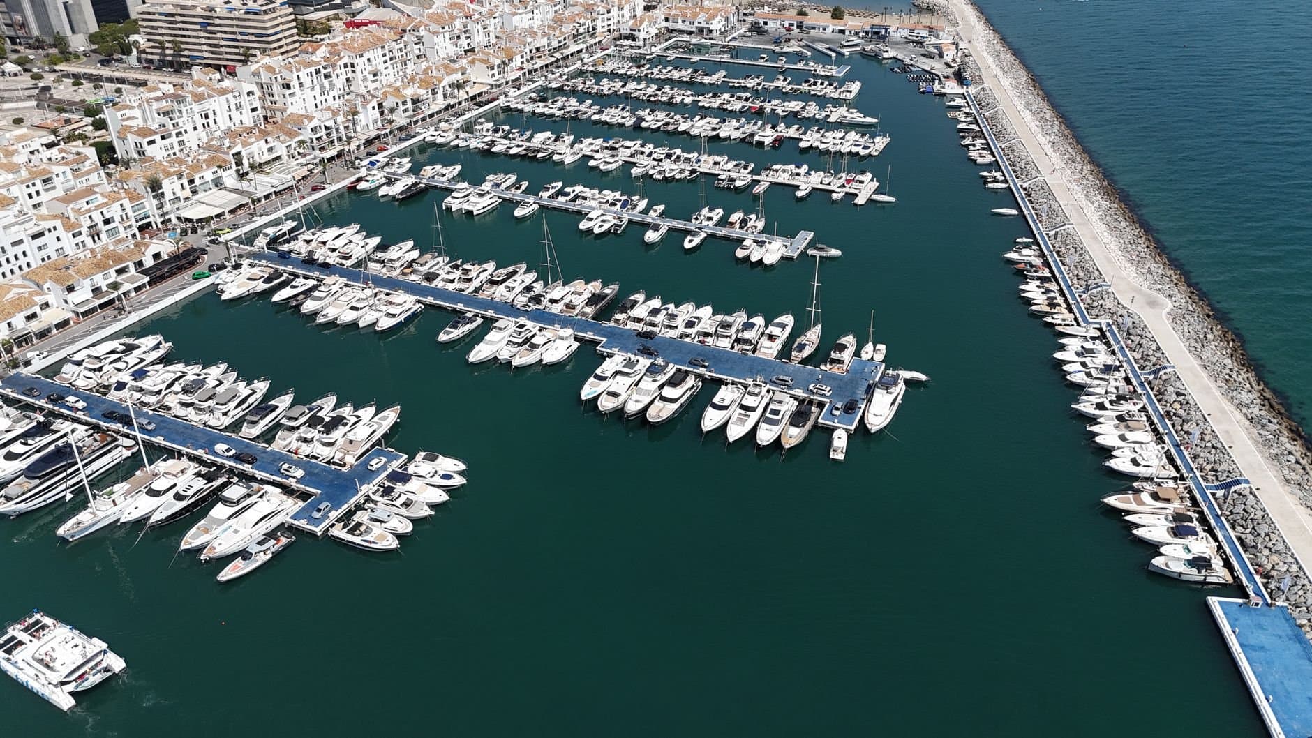 Stunning aerial view of a luxurious marina in Marbella, showcasing numerous yachts and boats.