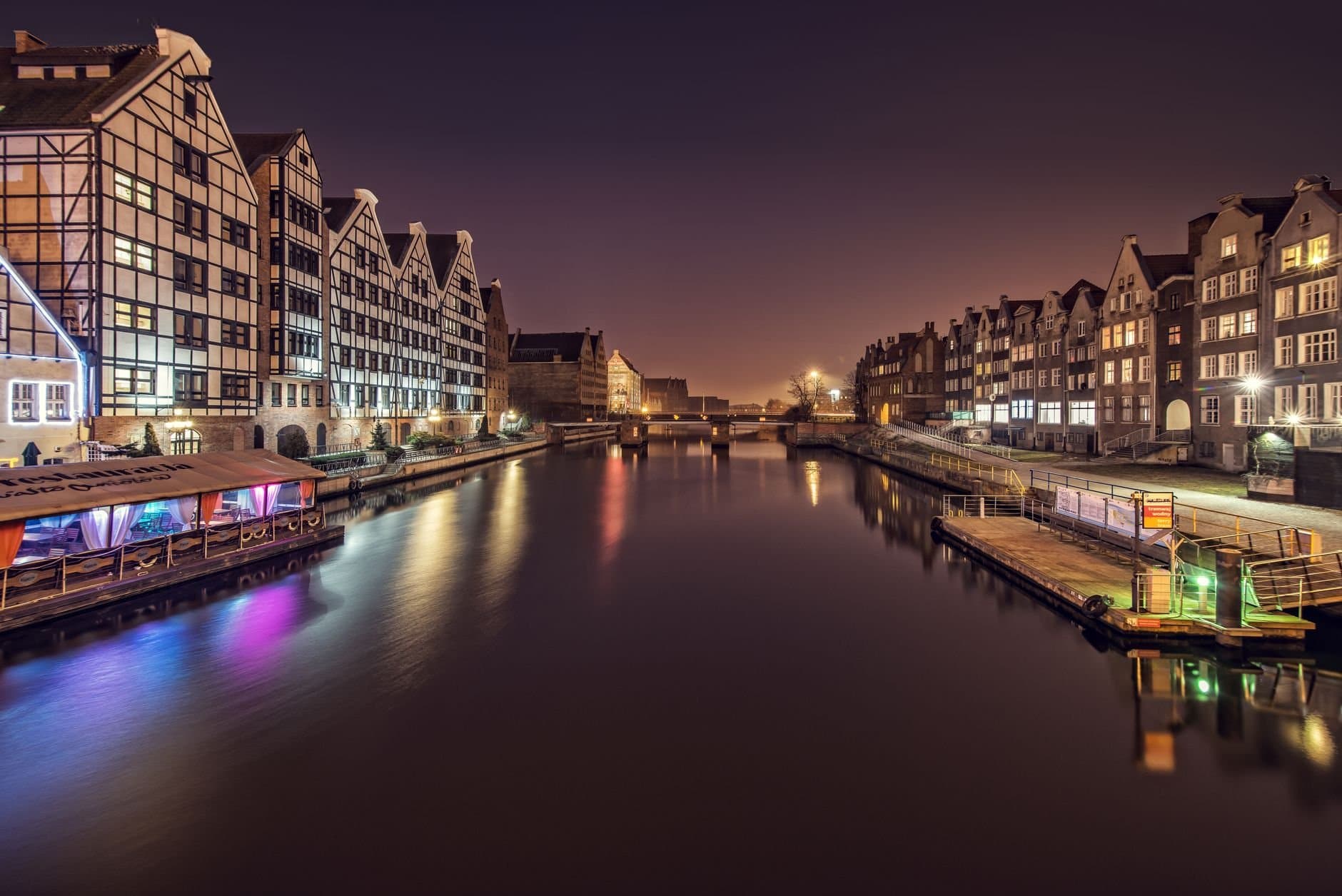 Water channel between multistage building exteriors and shiny lights at dusk in Amsterdam Netherlands