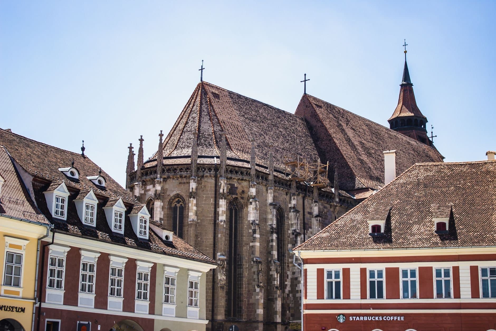 View of the Black Church in Brașov with distinct medieval architecture against a clear blue sky.