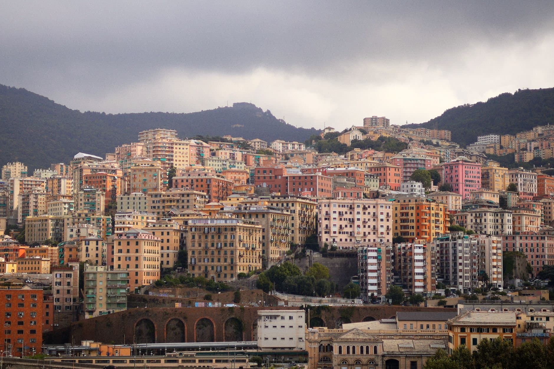 Scenic view of colorful residential buildings on Genoa's hillside under cloudy skies.