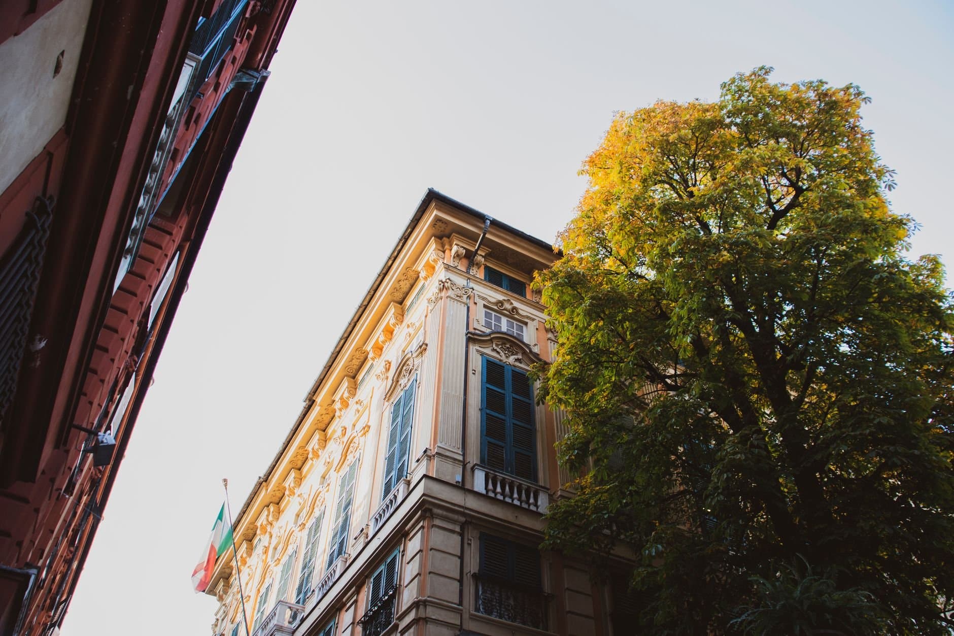 An elegant neoclassical building facade with Italian flag in Genoa, Italy.