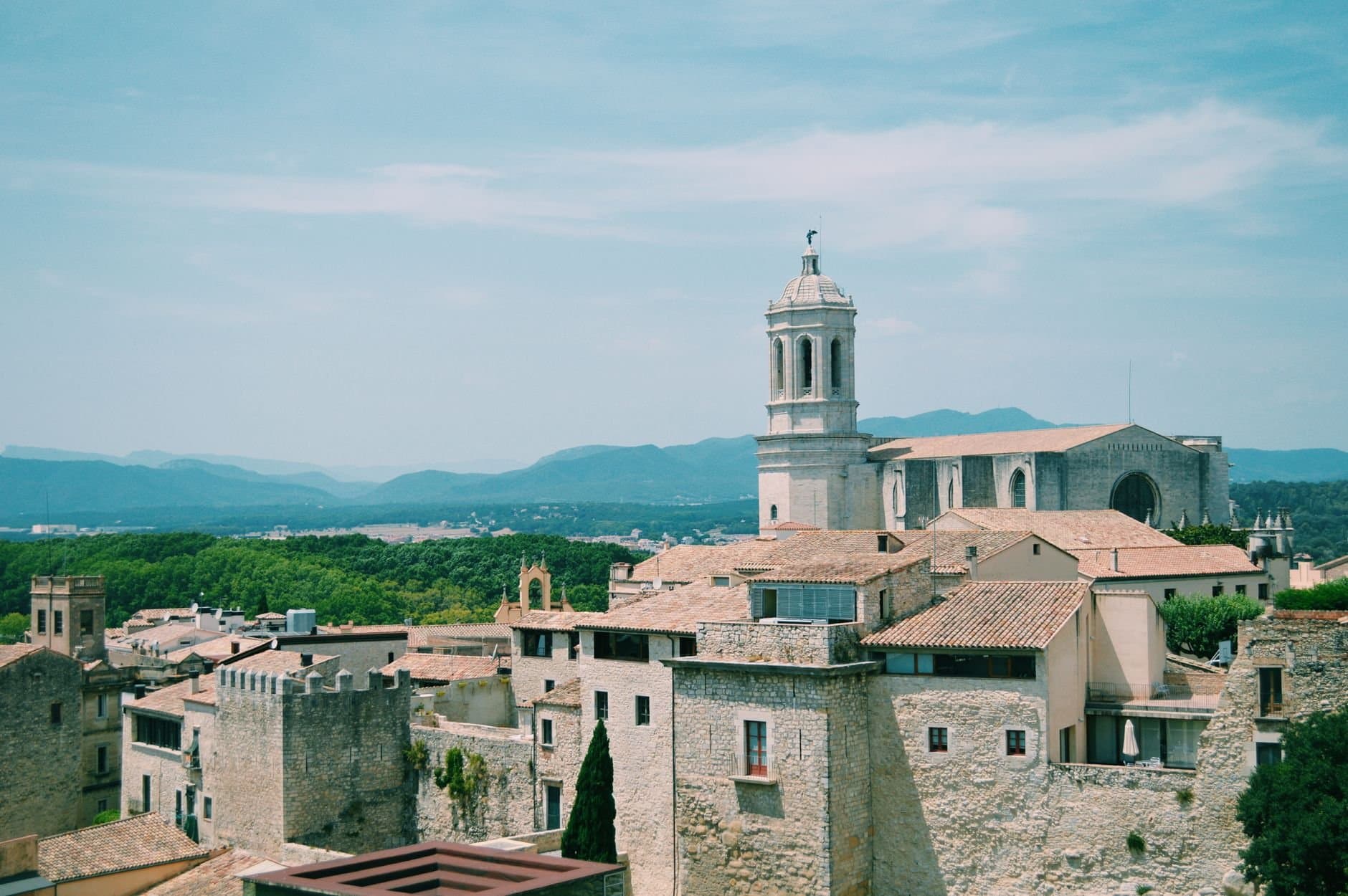 Scenic view of an old European town with a historic church, surrounded by mountains.