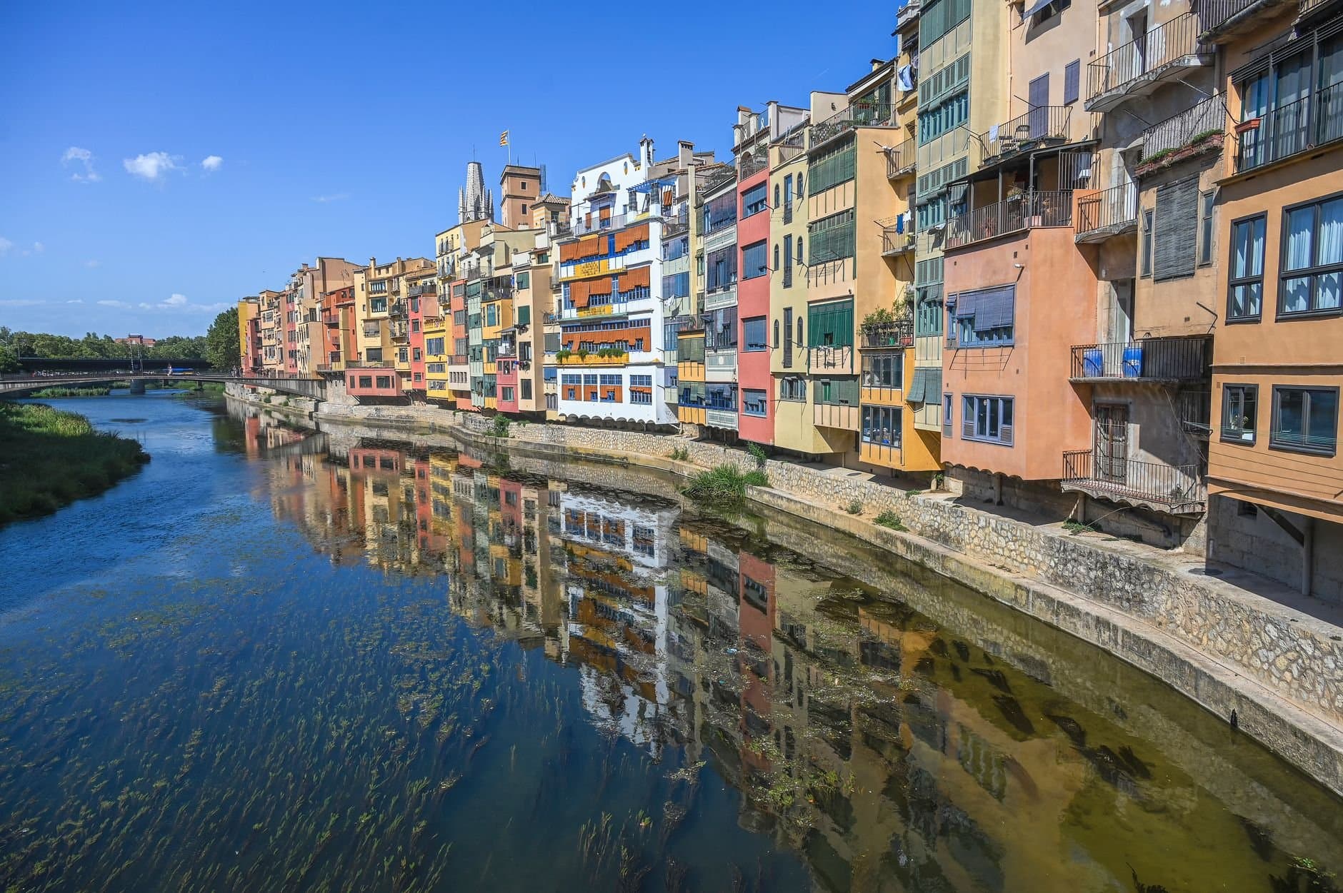 Vibrant riverfront view of colorful buildings along Onyar River in Girona, Spain.