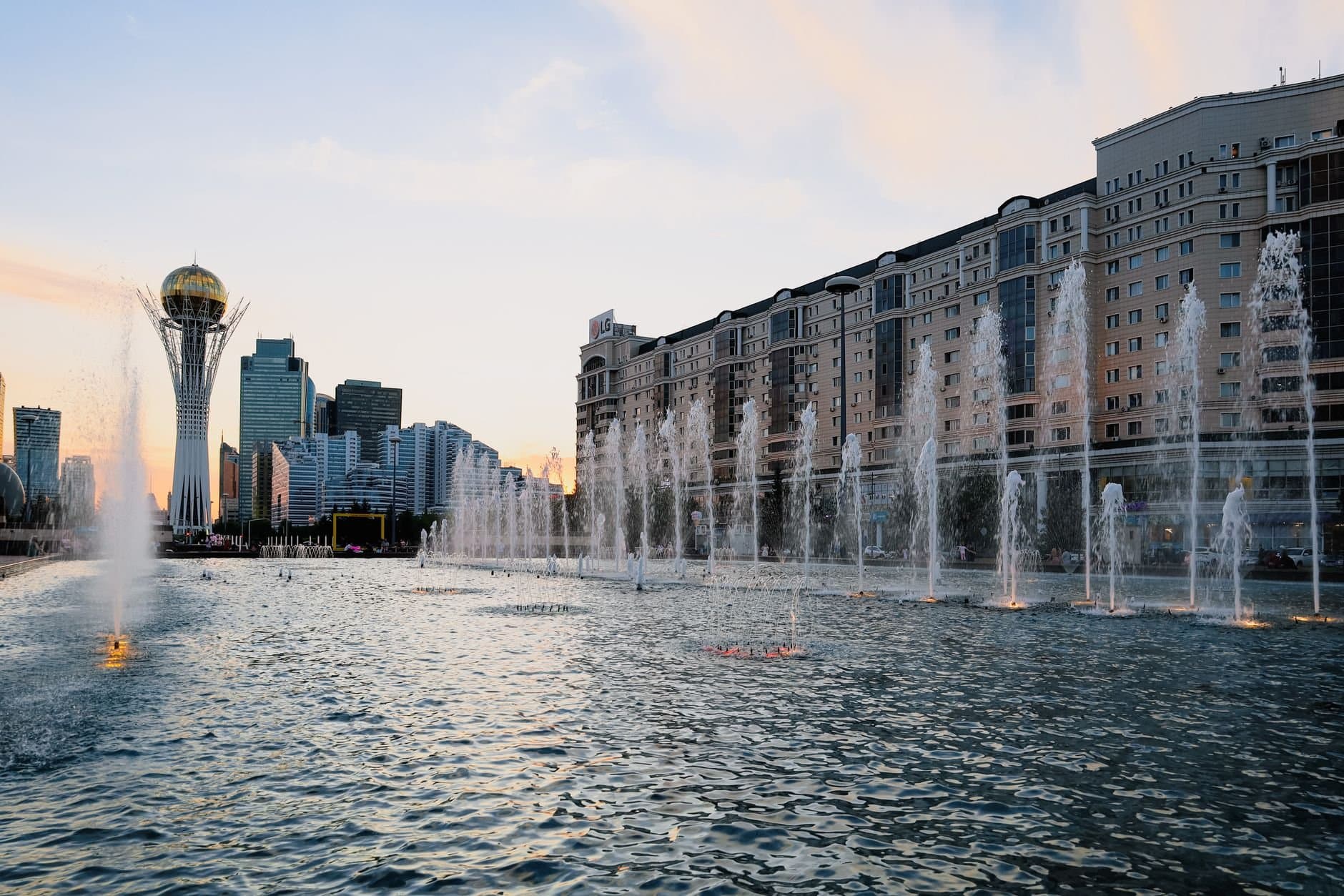 Stunning view of Astana's skyline featuring Baiterek Tower and fountains at sunset.