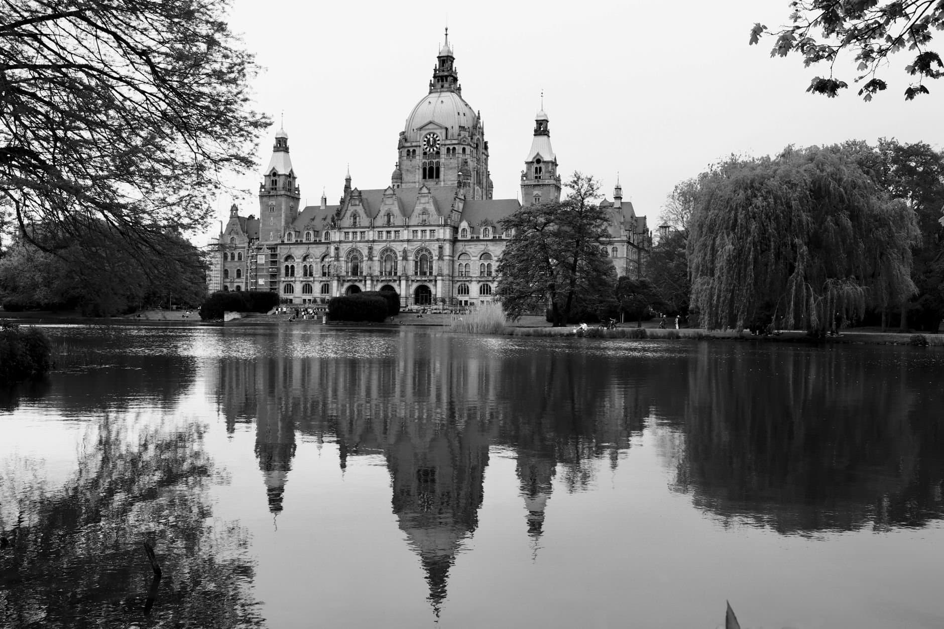 Black and white photo of New Town Hall in Hannover, reflected in the pond.