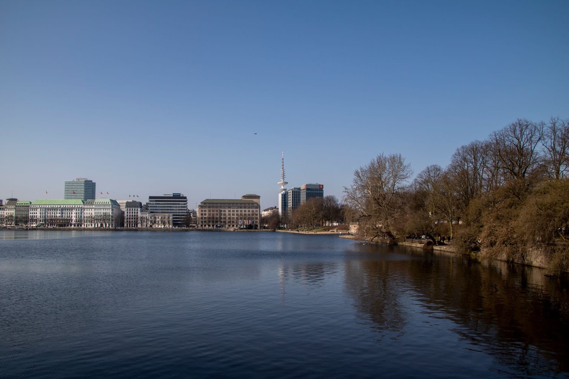 A beautiful view of the Binnenalster lake in Hamburg with clear blue skies and iconic landmarks.