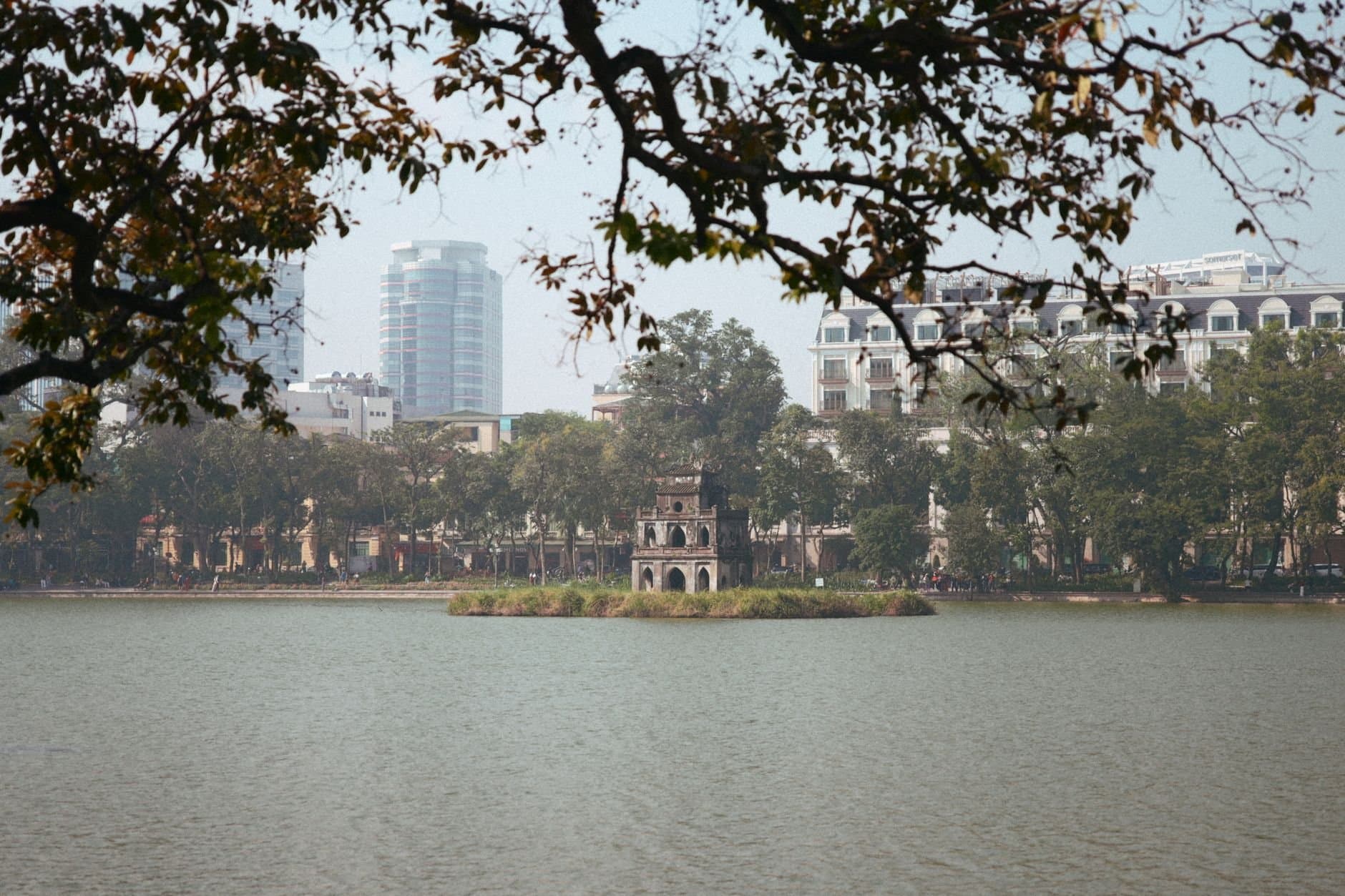 Peaceful view of Hoan Kiem Lake with Turtle Tower in Hanoi, Vietnam with city skyline.