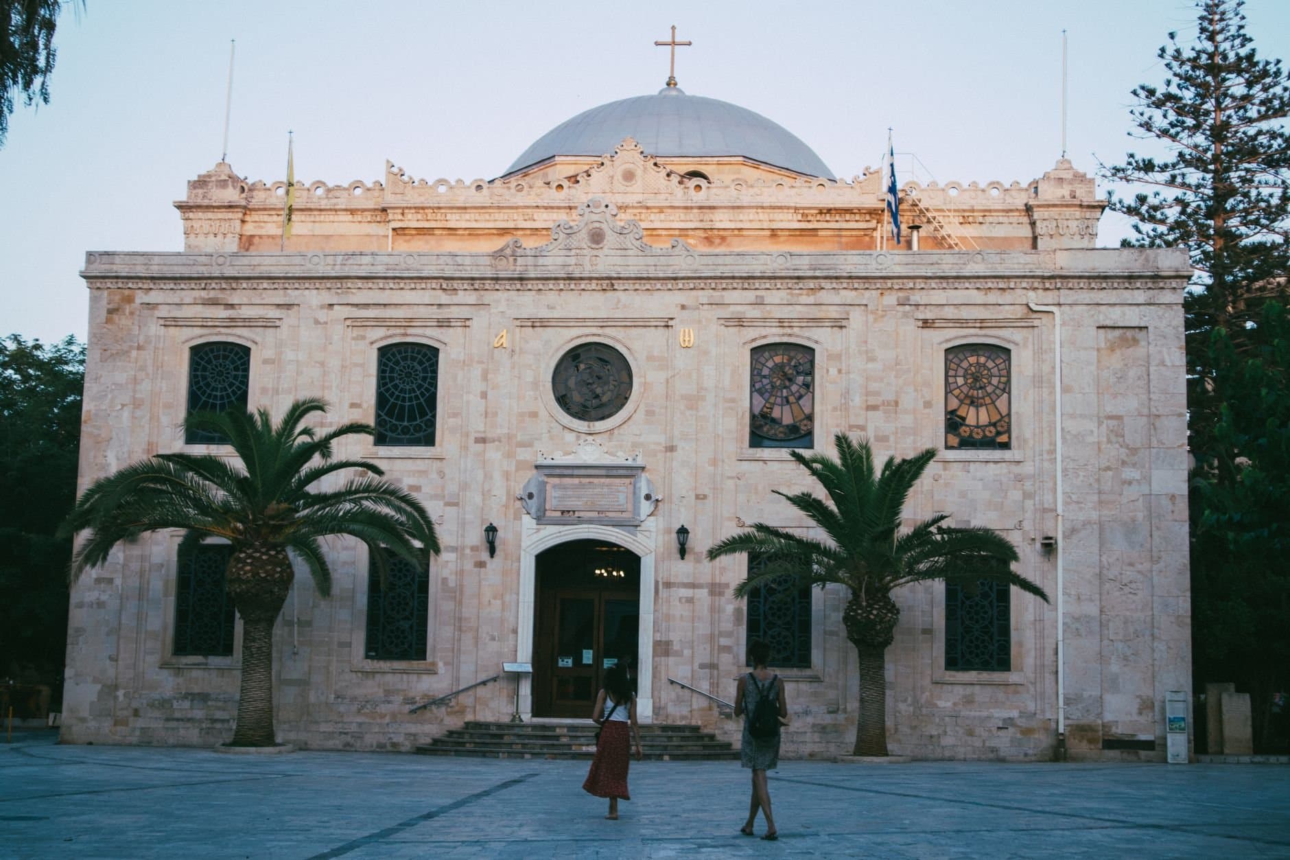 A beautiful historic church with a classic facade and palm trees at sunset.