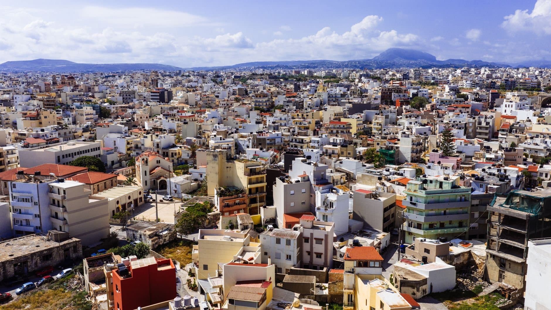 Discover the vibrant cityscape of Heraklion, Crete, captured from above with a stunning view of buildings and mountains.
