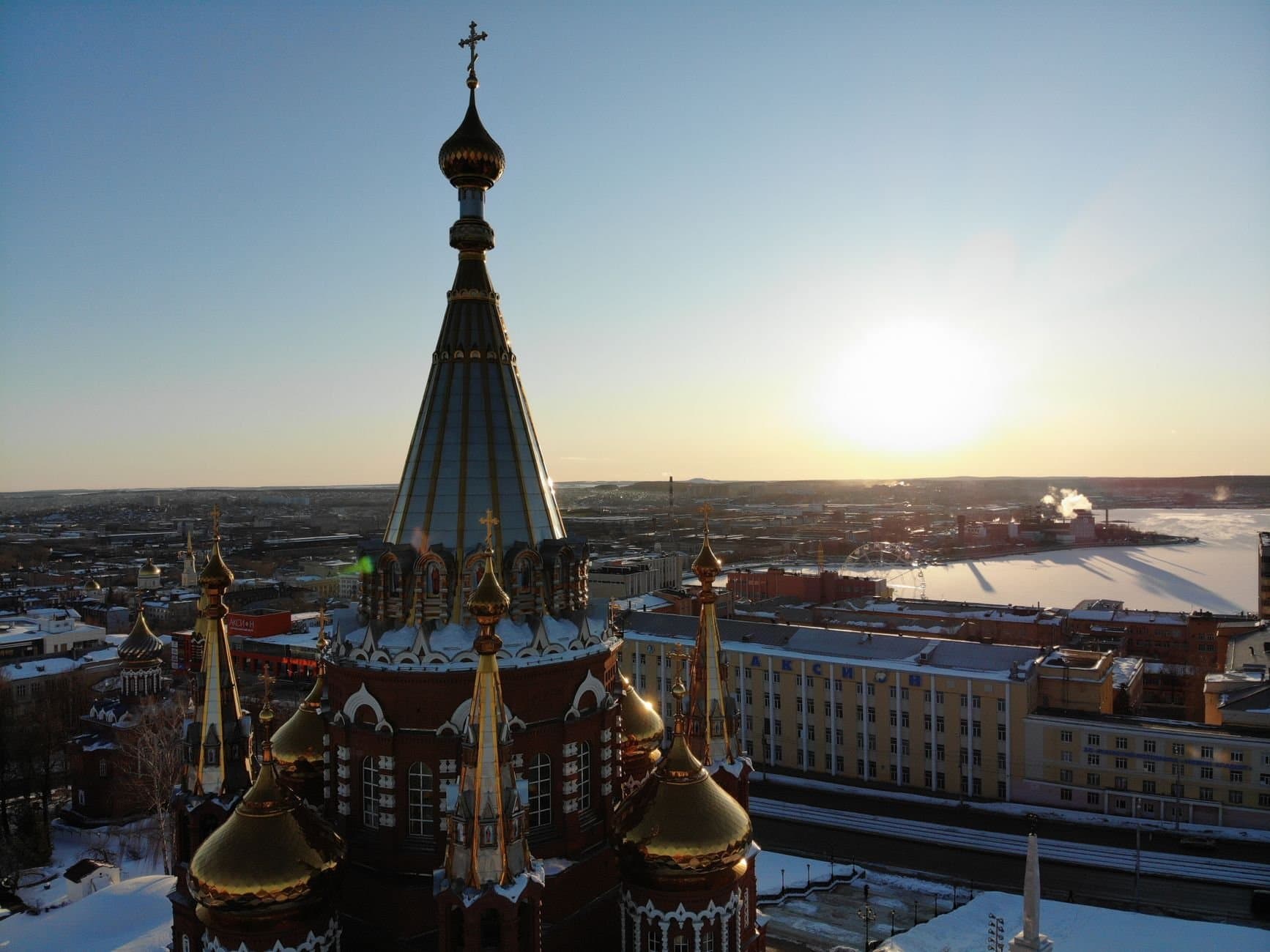 Aerial view of a historic cathedral in Udmurtia at sunset with a panoramic city skyline.