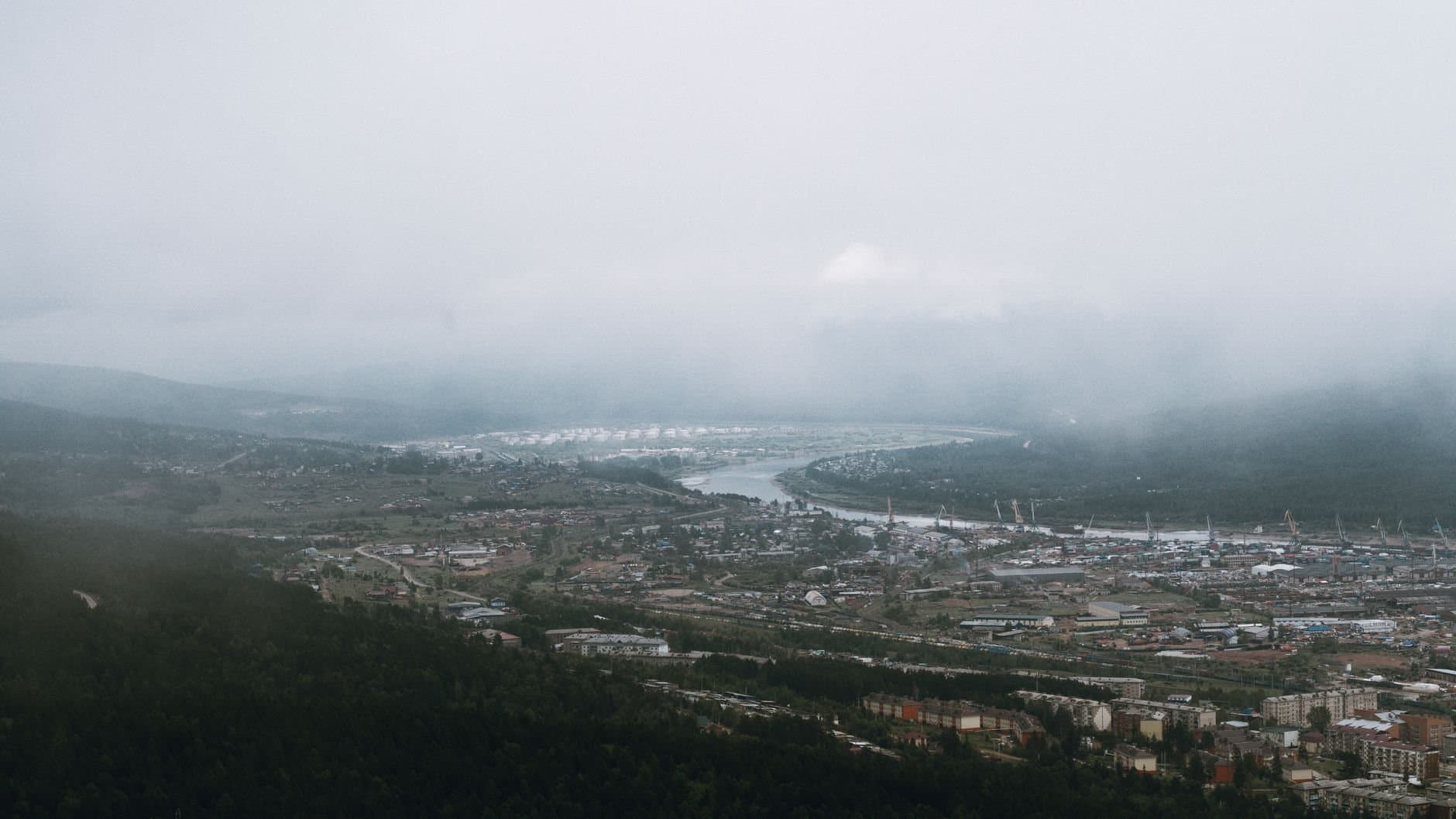 Scenic aerial view of Ust-Kut with fog, river, and mountains in a winter landscape.