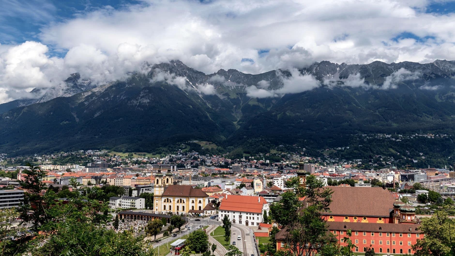 A breathtaking aerial view of Innsbruck, Austria, framed by majestic mountains and vibrant urban life.
