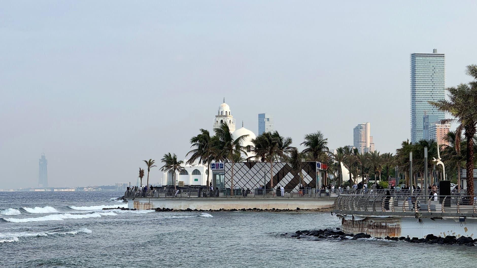 Morning view of Jeddah Corniche with palm trees and ocean waves, capturing Saudi Arabia's coastal beauty.