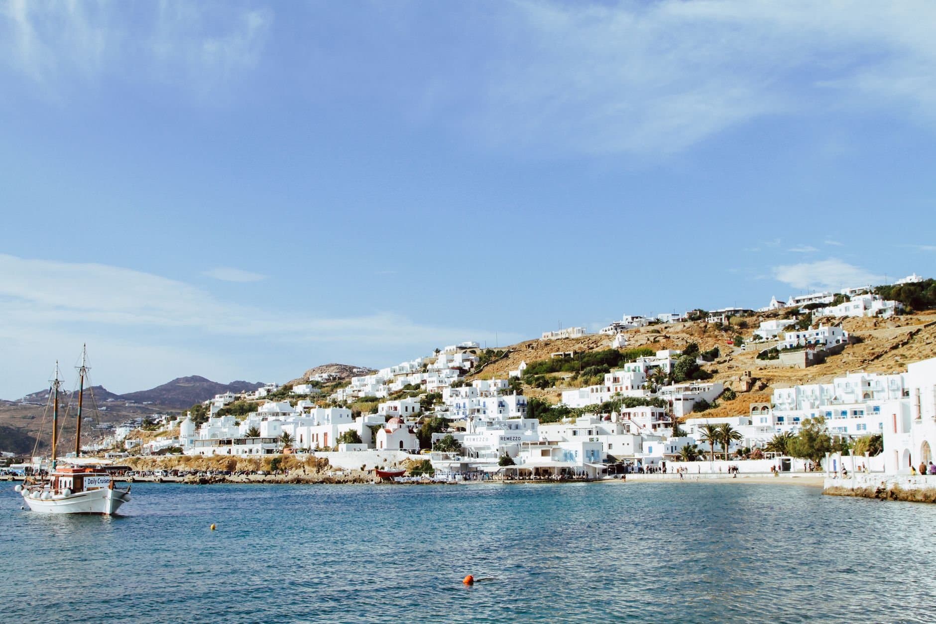 Beautiful view of Mikonos town with traditional architecture and clear blue water harbor.