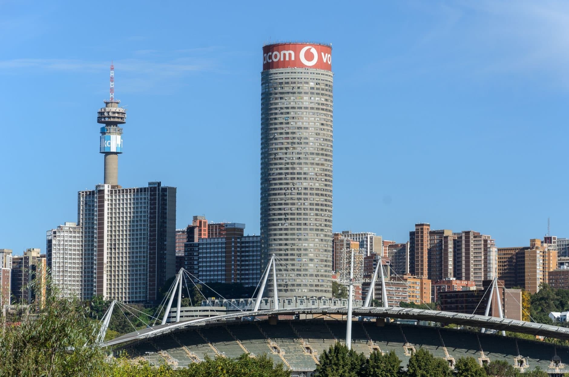 Skyline view of Johannesburg with iconic Ponte Tower under a blue sky.