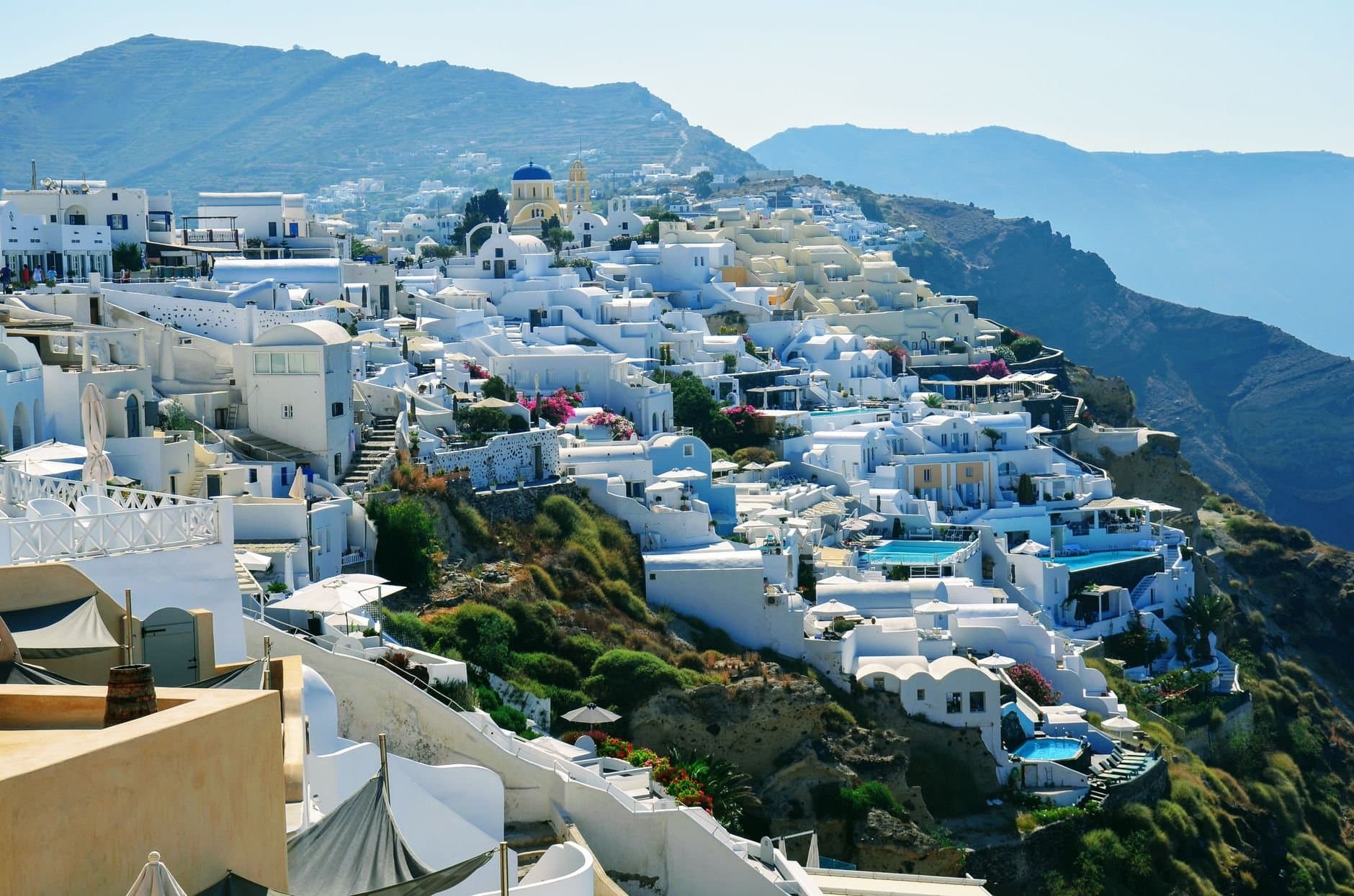 A stunning landscape of Santorini, Greece, featuring white buildings and blue domes against the Aegean Sea.