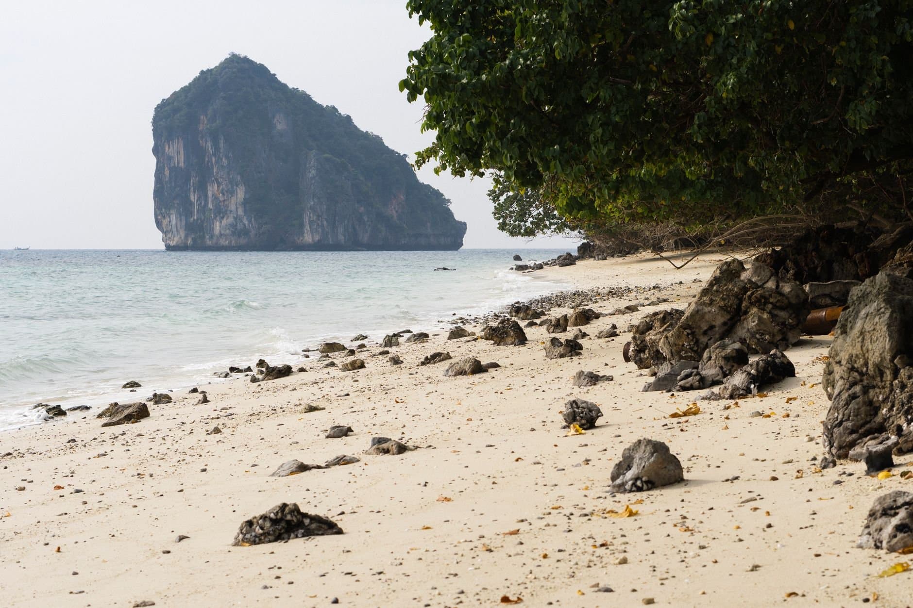 Tranquil Krabi beach with limestone cliff and turquoise waters.