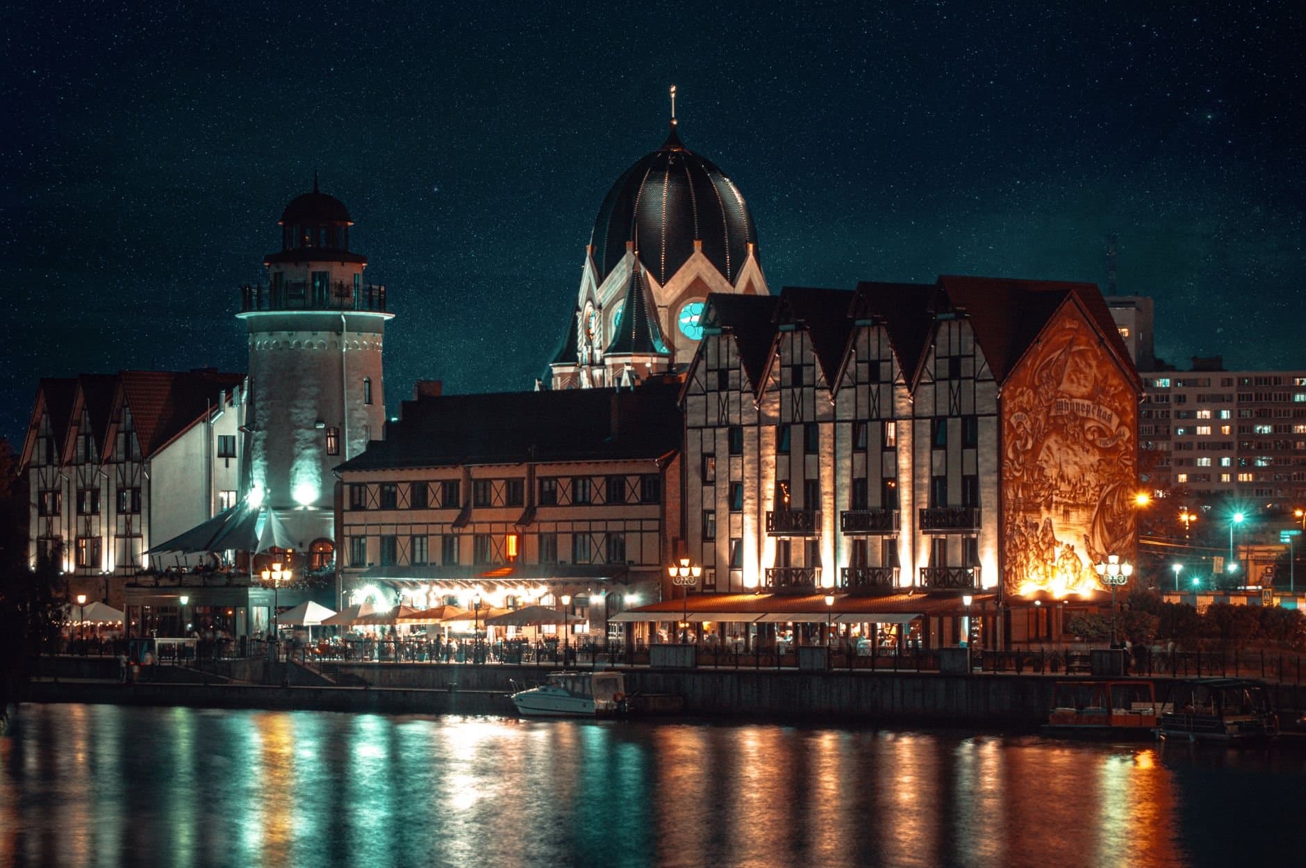 Illuminated waterfront view of Kaliningrad, Russia at night, reflecting on the Pregolya River.