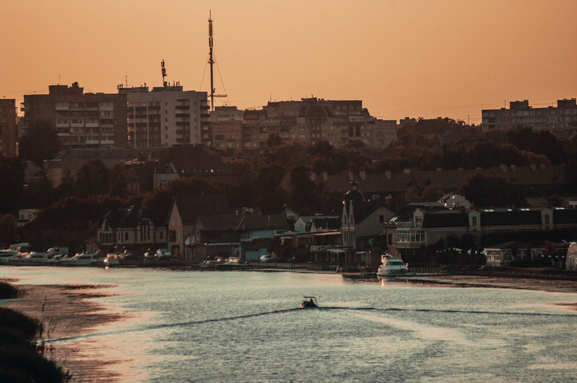 Peaceful evening view of Kaliningrad's harbor with boats and buildings at sunset.
