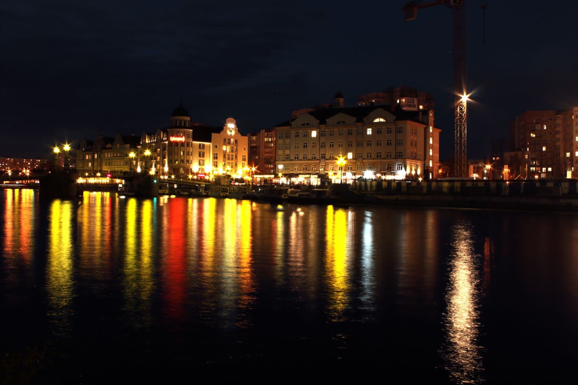 Beautiful night view of Kaliningrad's waterfront with city lights reflecting in the water.