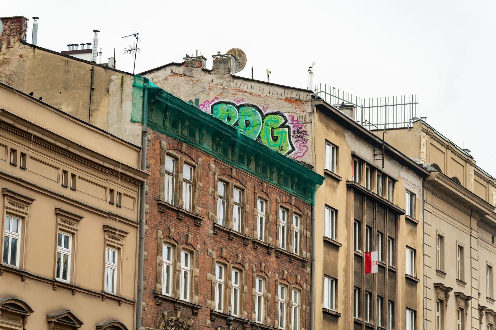 Colorful graffiti on historic buildings in Kraków, Poland, showcasing urban art contrasting old architecture.