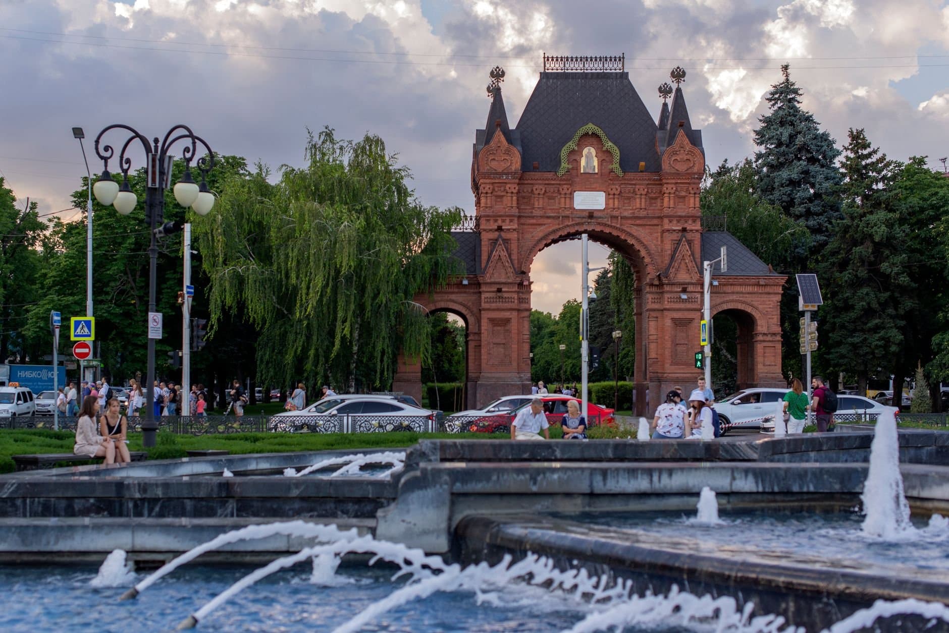 Triumfalnaya Arka in Krasnodar, Russia, with a bustling city scene and fountain.