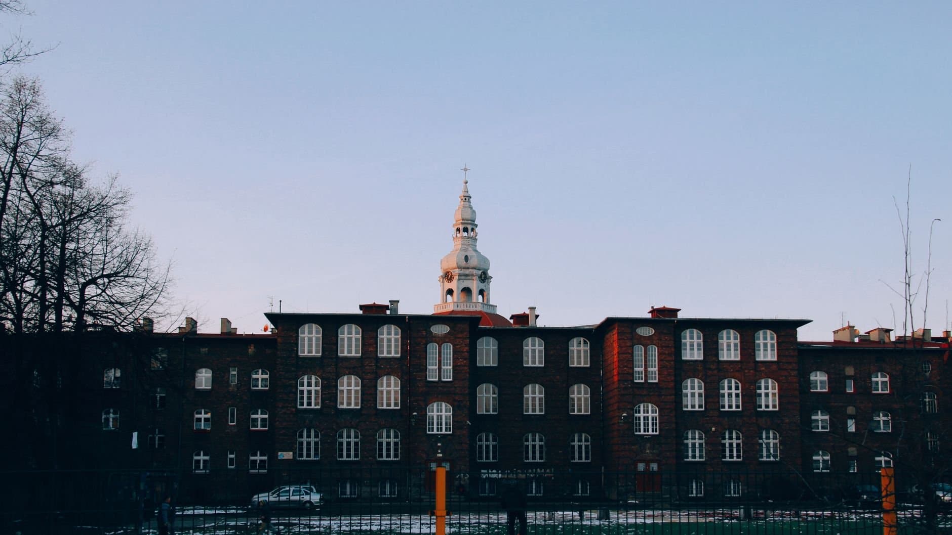 Twilight view of a historic building with a tower in Katowice, Poland.